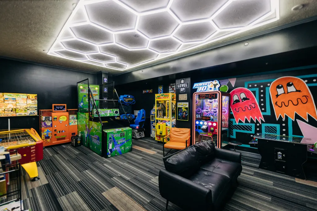 Arcade games and lounge seating under hexagon lights in the game room