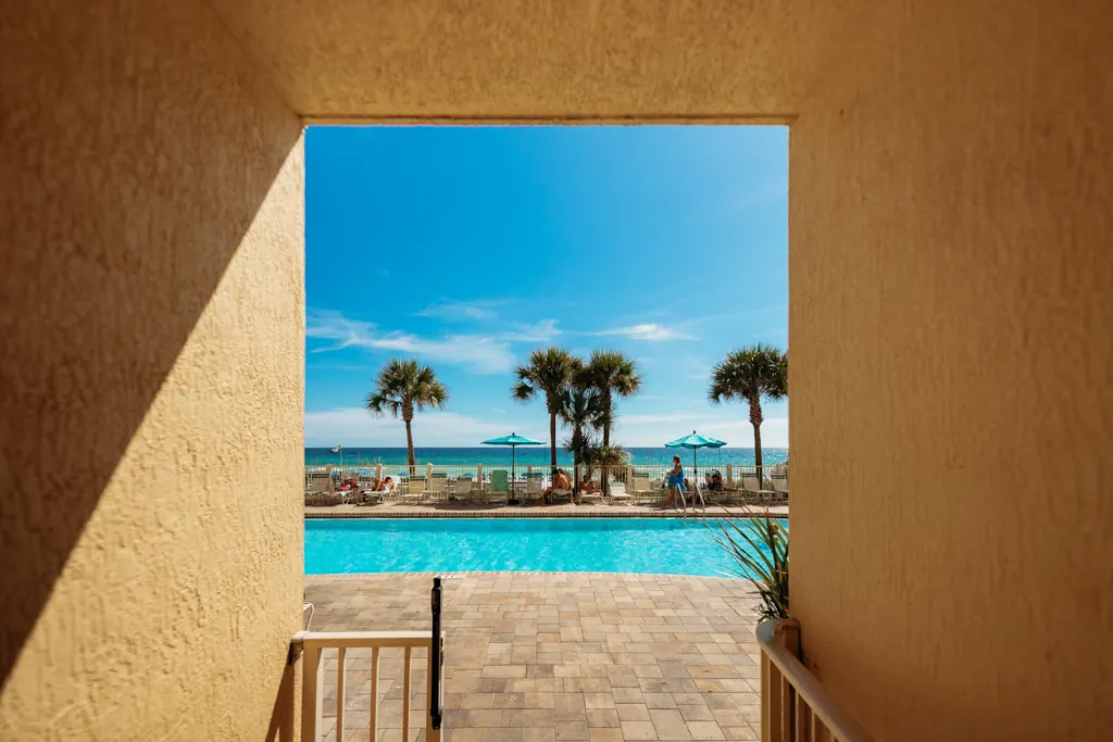 View through an archway to the pool, palms and the Gulf