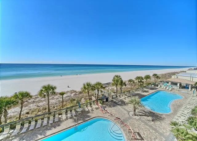 View from a Gulf Crest balcony down to the pools, palm trees, beach and Gulf