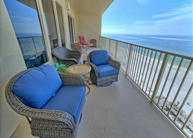 Oversized balcony with blue wicker chairs high above the emerald Gulf of Mexico