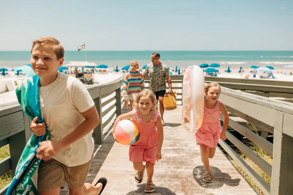 Smiling boy carrying a beach towel up the boardwalk from the beach