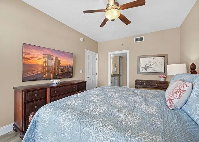 Condo bedroom with coastal bedding, a ceiling fan and a window to the Gulf