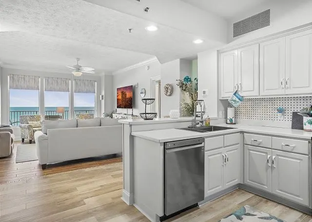 Condo kitchen with white cabinets and an island opening to the living room and Gulf view