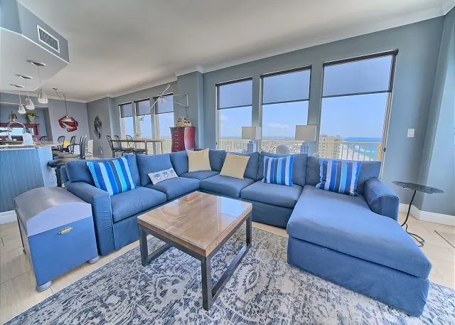 Condo living room with a blue sectional sofa and a wall of windows over the Gulf