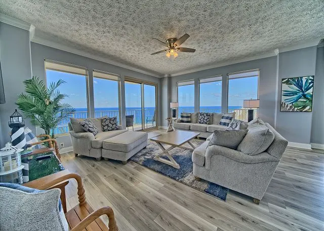 Corner condo living room with gray sofas and windows on two sides overlooking the Gulf