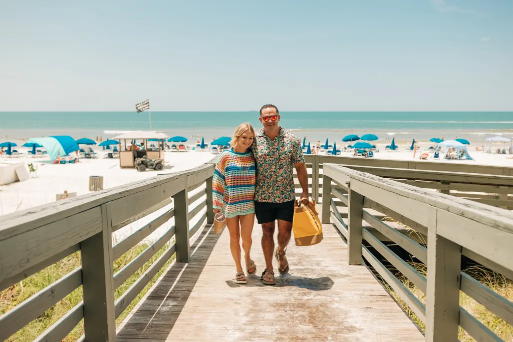Couple with a beach bag on the boardwalk at Gulf Crest Condominiums, beach and Gulf behind them