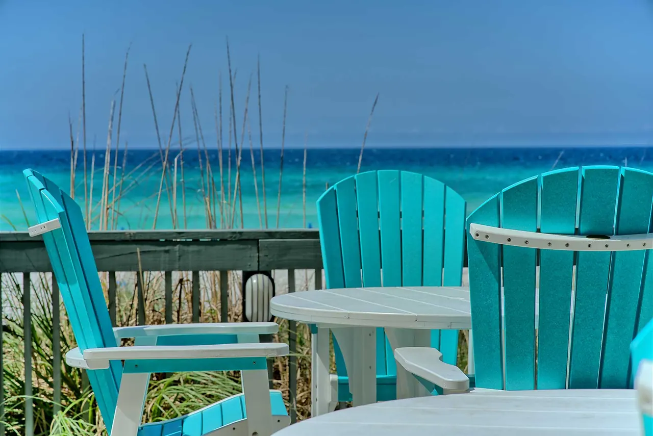 Turquoise Adirondack chairs and tables on the pool deck overlooking the Gulf of Mexico