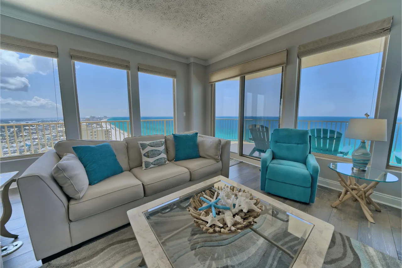 Condo living room with sofa and armchairs facing floor-to-ceiling windows and the Gulf