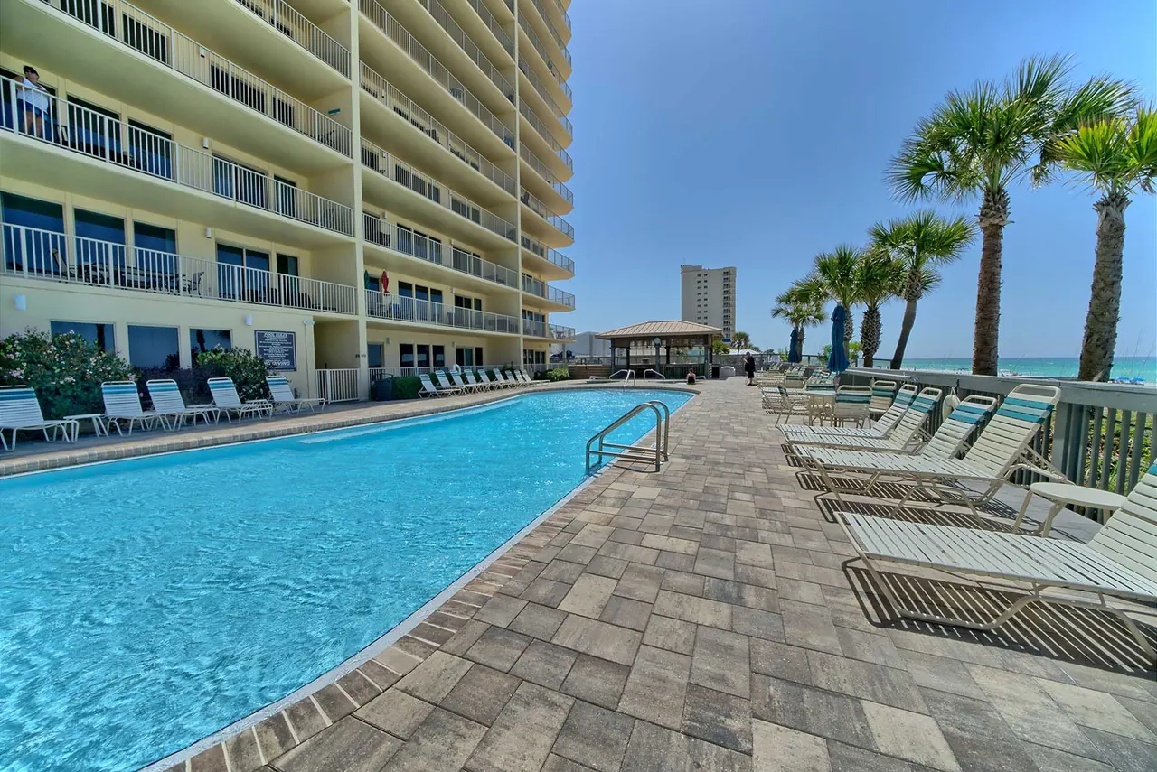 Long pool and lounge chairs along the Gulf Crest tower with palm trees