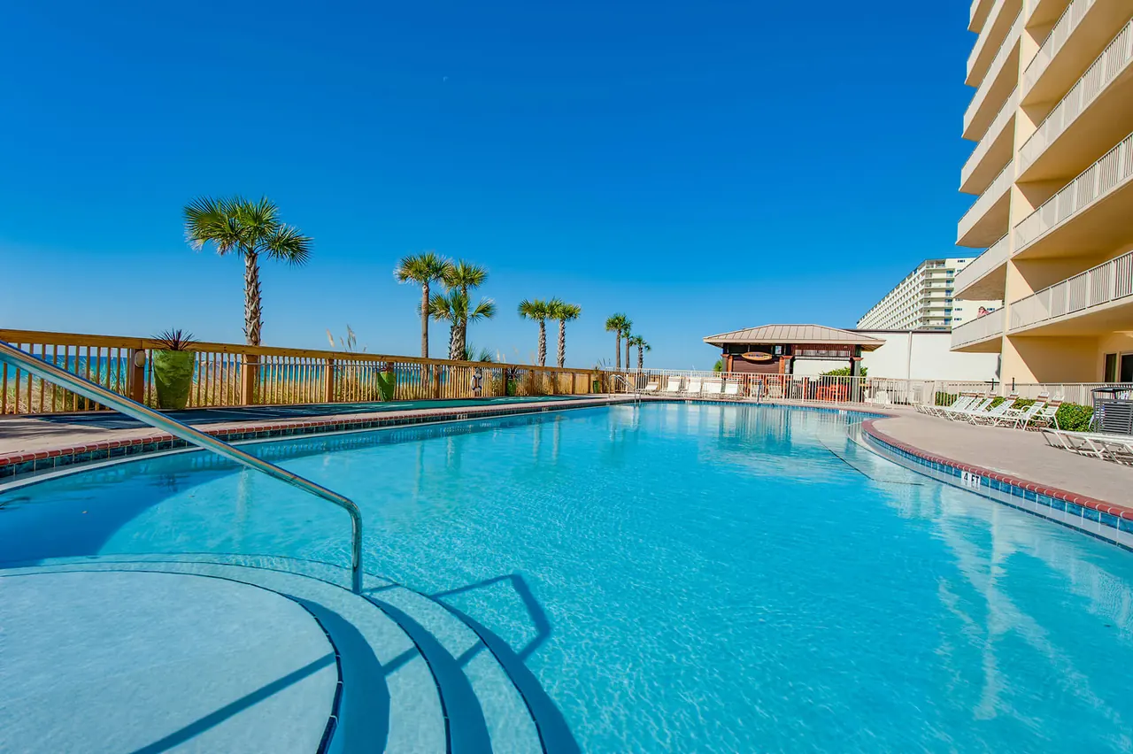Large beachside pool with palm trees and a gazebo beside the Gulf Crest tower