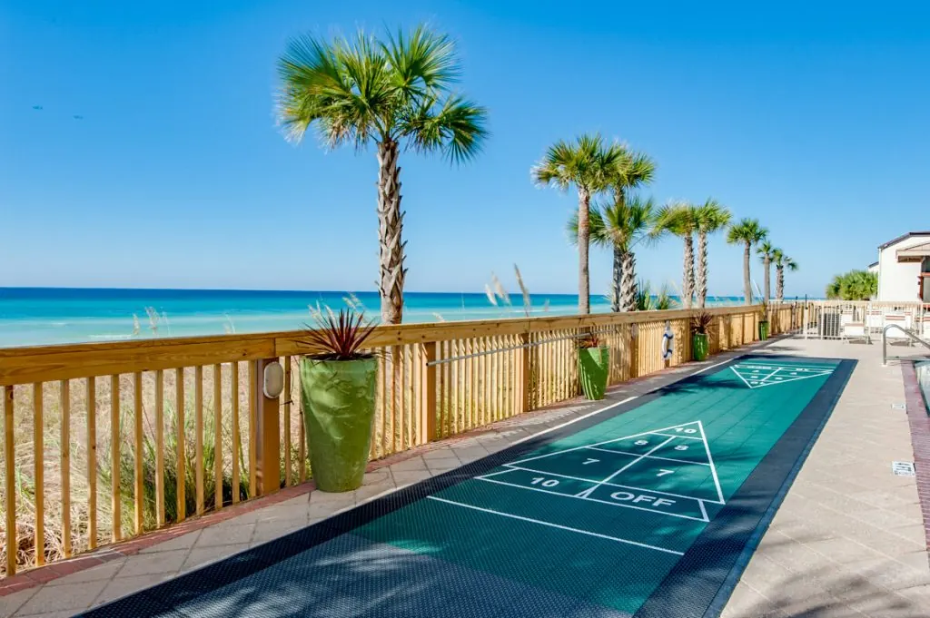 Shuffleboard court on the deck beside the dunes, with palm trees and the Gulf beyond