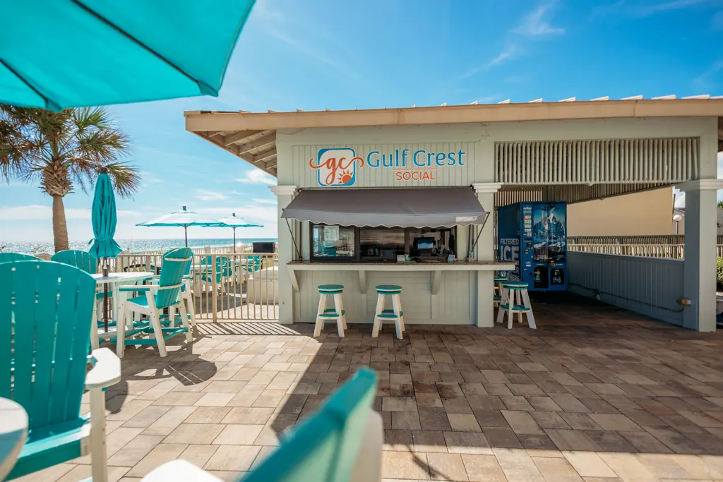 Gulf Crest Social bar on the pool deck with teal chairs and tables