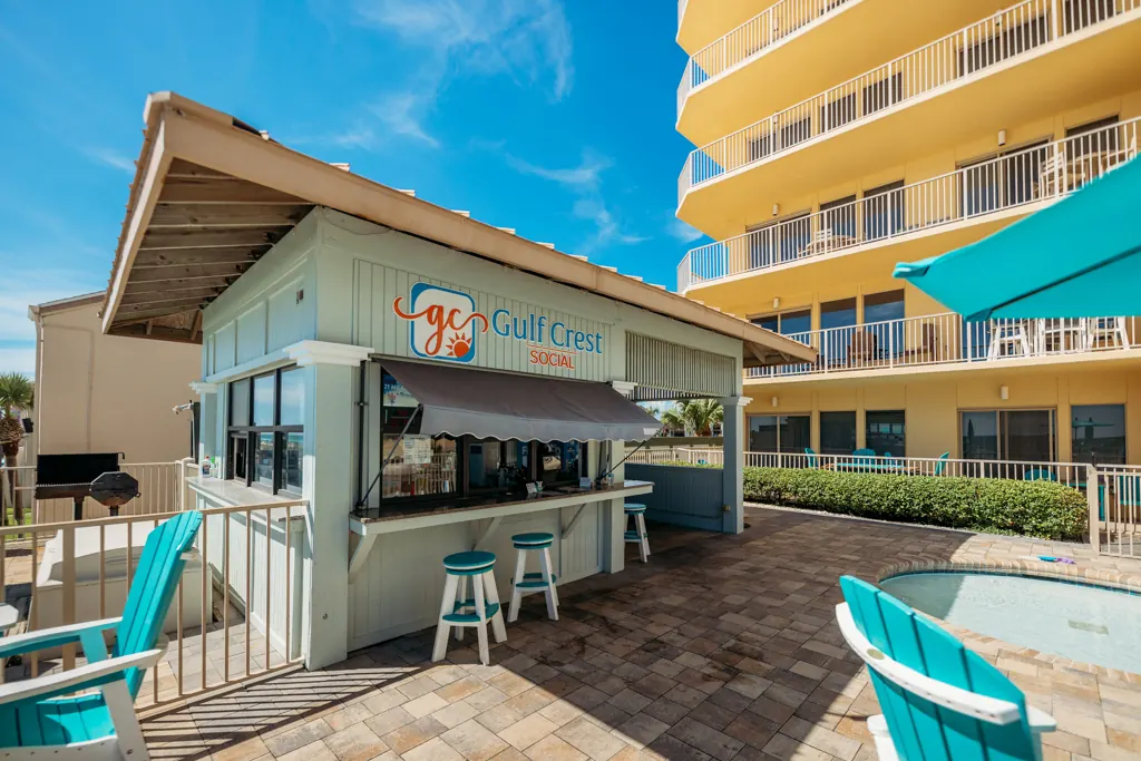 Gulf Crest Social poolside bar with stools and umbrellas beside the tower