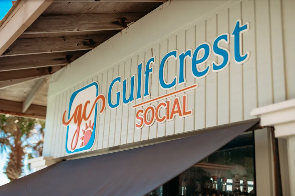 Gulf Crest Social sign with the gc sun logo above the poolside bar