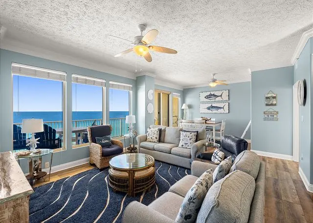 Bright Gulf-front living room at Gulf Crest with sofas, a ceiling fan and floor-to-ceiling windows over the Gulf of Mexico