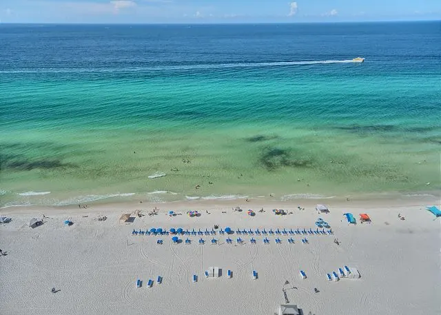 Balcony view of turquoise Gulf water and beach umbrellas lining the shore