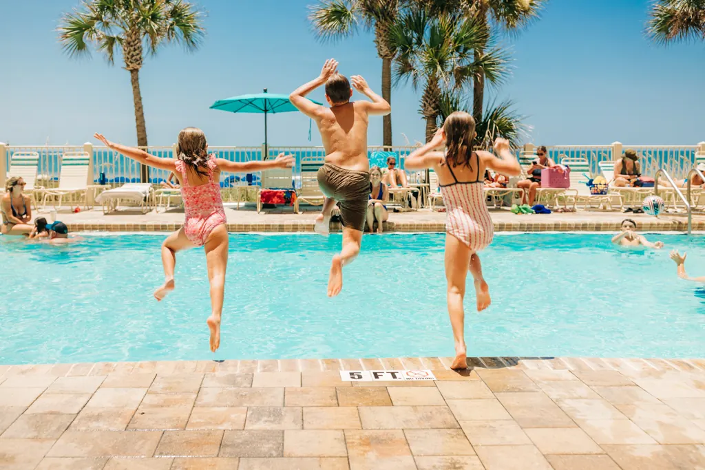 Kids jumping into the pool at Gulf Crest Condominiums on a sunny day