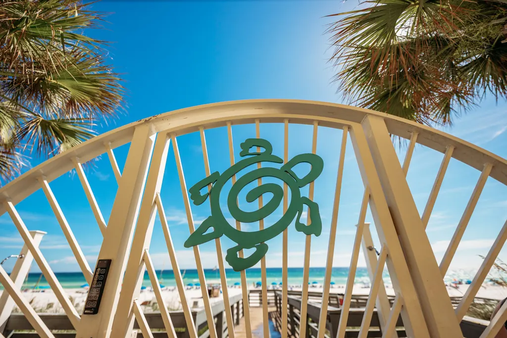 Sea turtle emblem on the Gulf Crest beach gate with palms and the Gulf