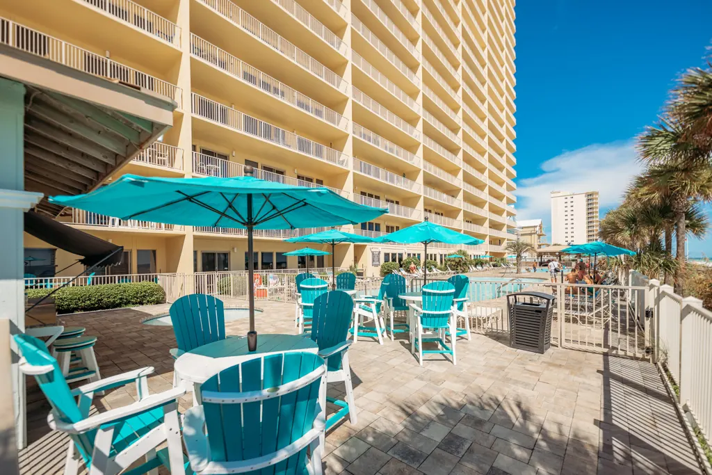 Shaded tables and chairs on the pool deck alongside the tower