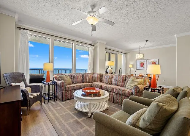 Spacious condo living room with a sectional sofa and Gulf-view windows at Gulf Crest Condominiums