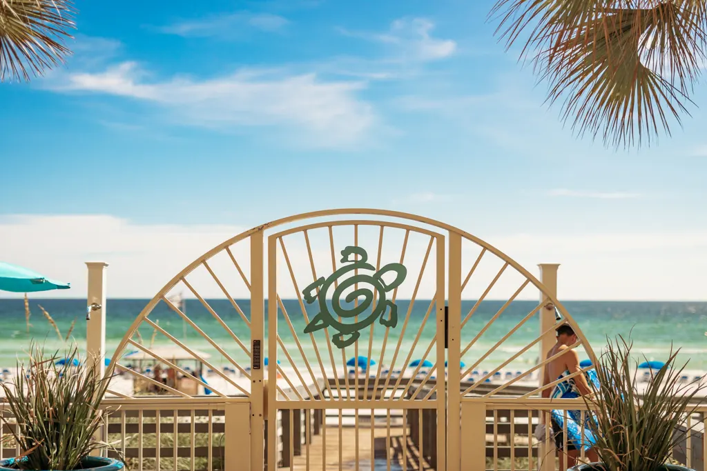 Sunburst beach gate with a sea turtle emblem leading to the beach